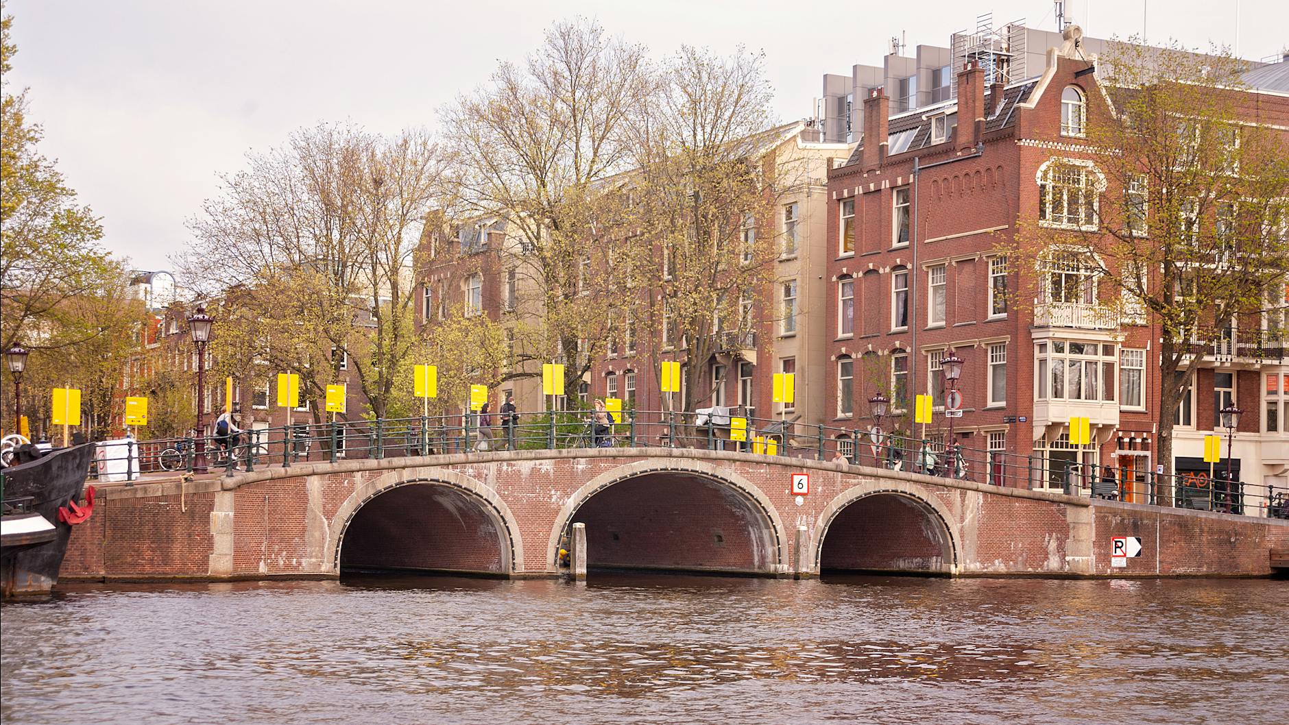 Ceglany most nad kanałem w Amsterdamie w słoneczny dzień