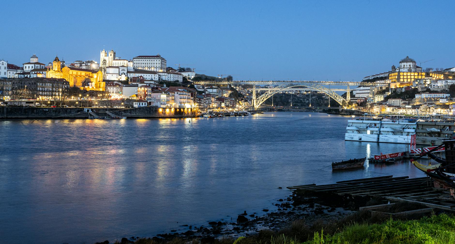 Nocny widok na oświetlony most Dom Luís I nad rzeką Douro w Porto