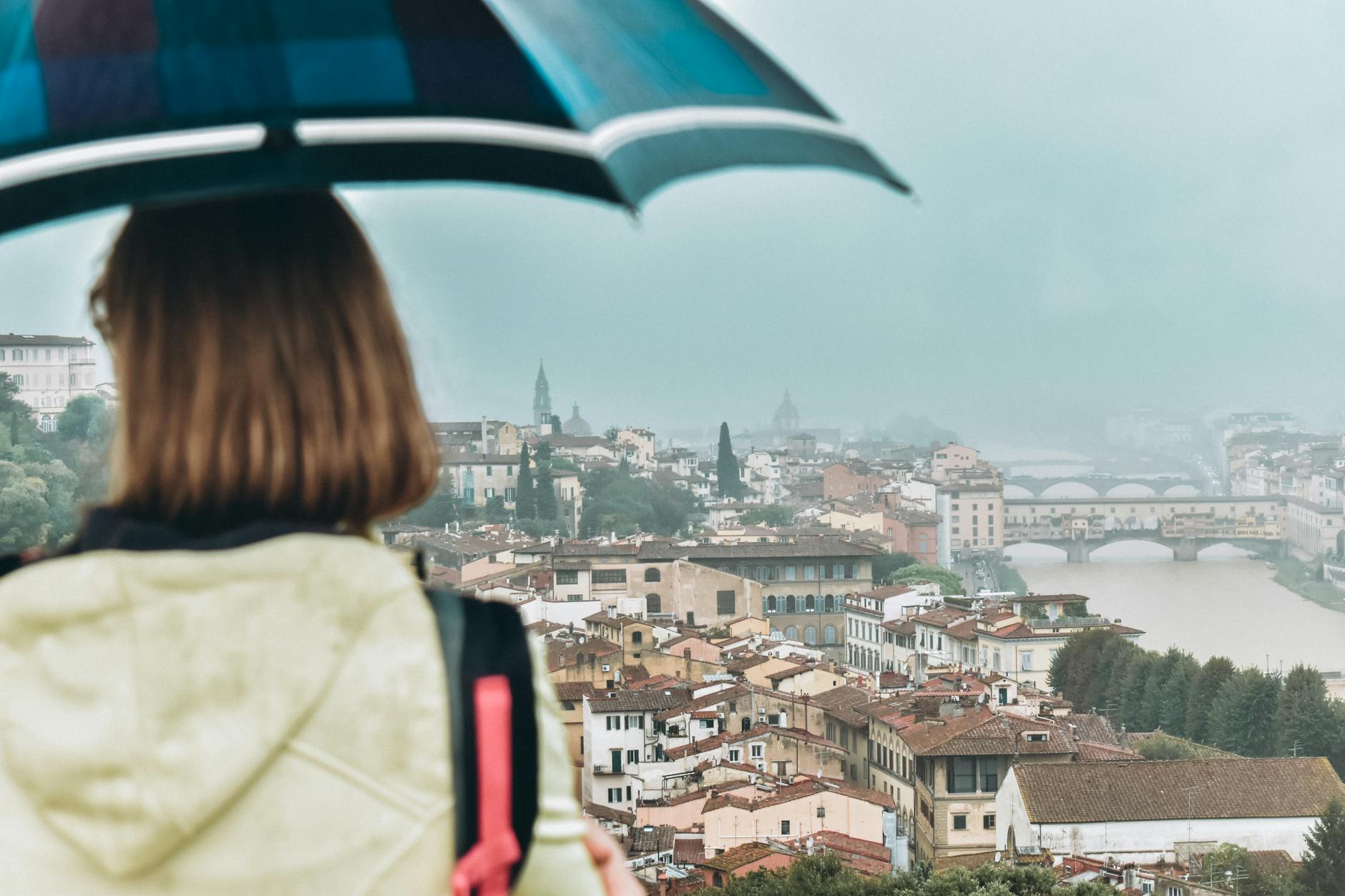 Osoba z parasolem patrzy na Ponte Vecchio i panoramę Florencji