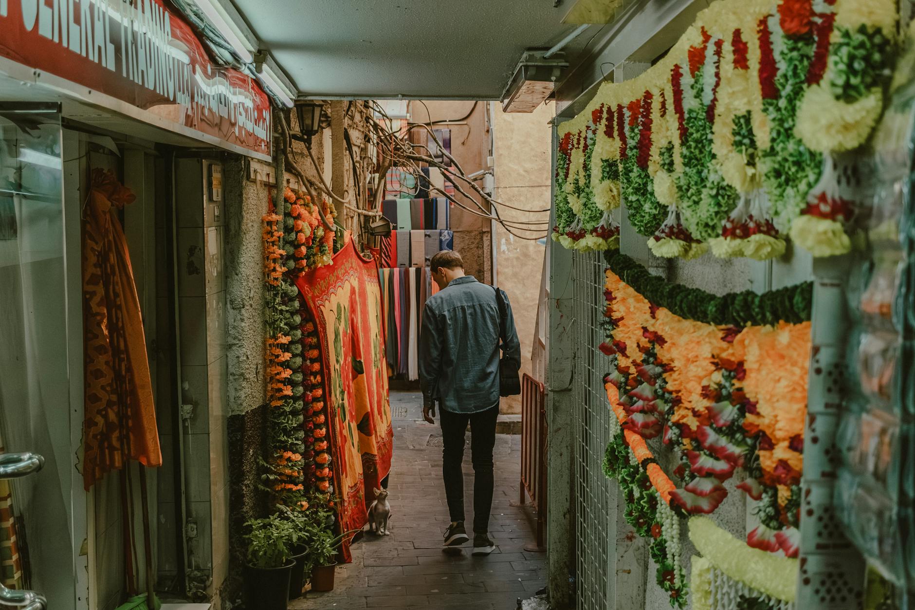 Tłoczna alejka dubajskiego bazaru z kolorowymi tkaninami i girlandami